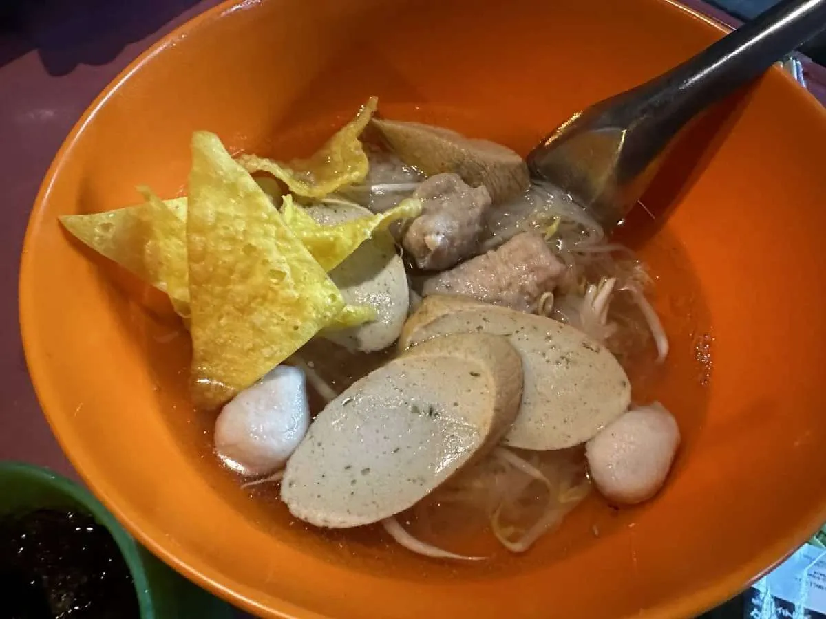 タイ風ラーメンの一種。麺は春雨風で、スープは魚介系の出汁。これにナンプラー、唐辛子、唐辛子入りの酢など何種類かの調味料で味を調整して食べる。いくつかの練り物が乗って、これまた美味かった。©望月俊典