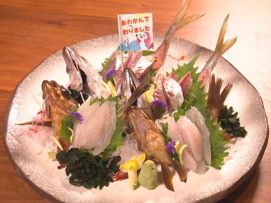 良型アジとメバルのお造り！お刺身に刺さった旗には「あわかんで釣りました」の文字。お造りのほか、アジのお寿司、そして高橋がどうしても食べたかったというなめろうをいただいた。淡路島特産の玉ねぎが入っていて絶品なんだとか！&copy;釣りビジョン