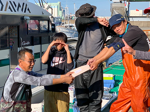 セミファイナルの切符を渡す村上利行船長と切符を手にする櫻井さん(右)